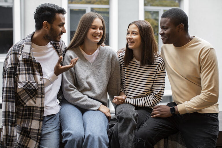 Grupo de jovens conversando e sorrindo ao ar livre.