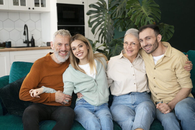 Família sorridente sentada no sofá de casa, abraçando-se